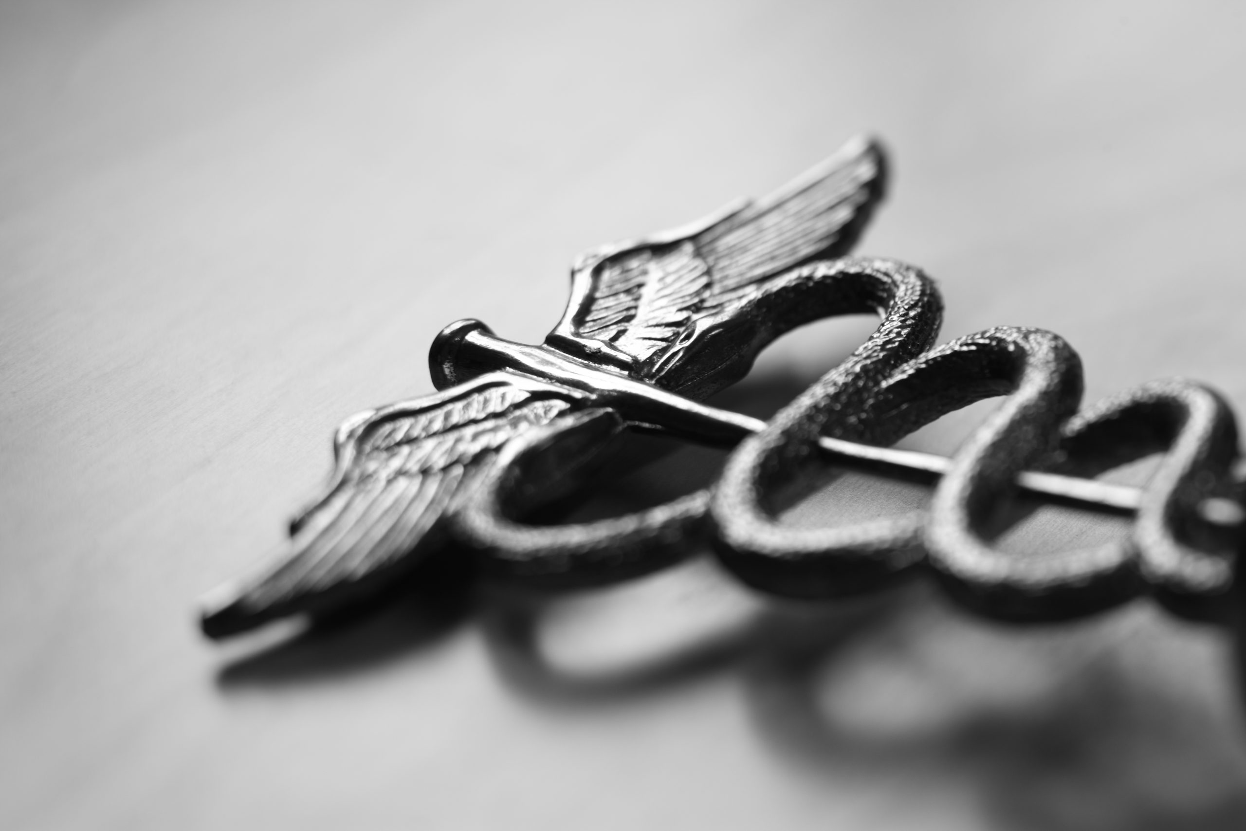 A Caduceus symbol on a gray background.